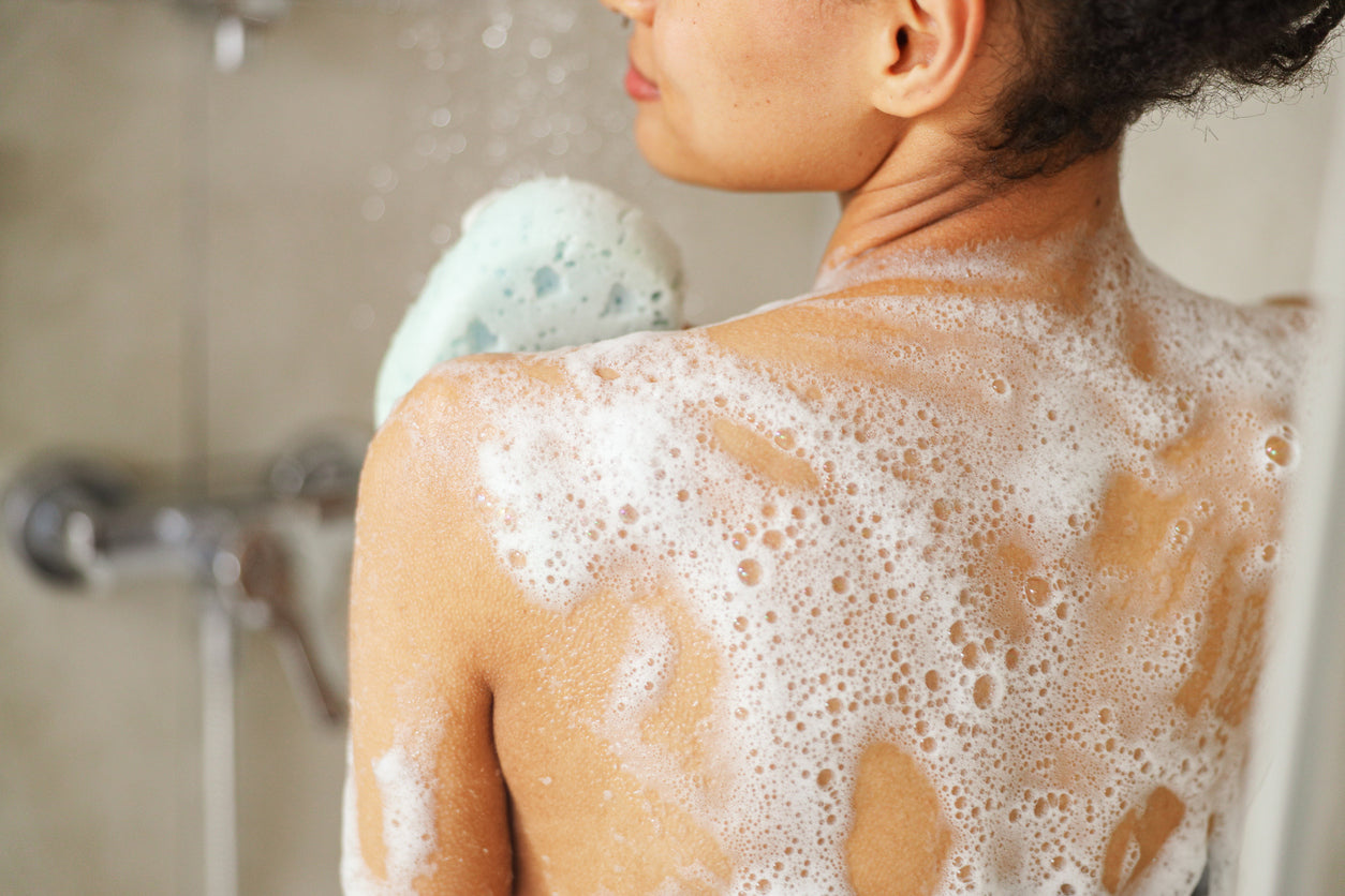 dos de femme sous la douche recouvert de mousse de savon