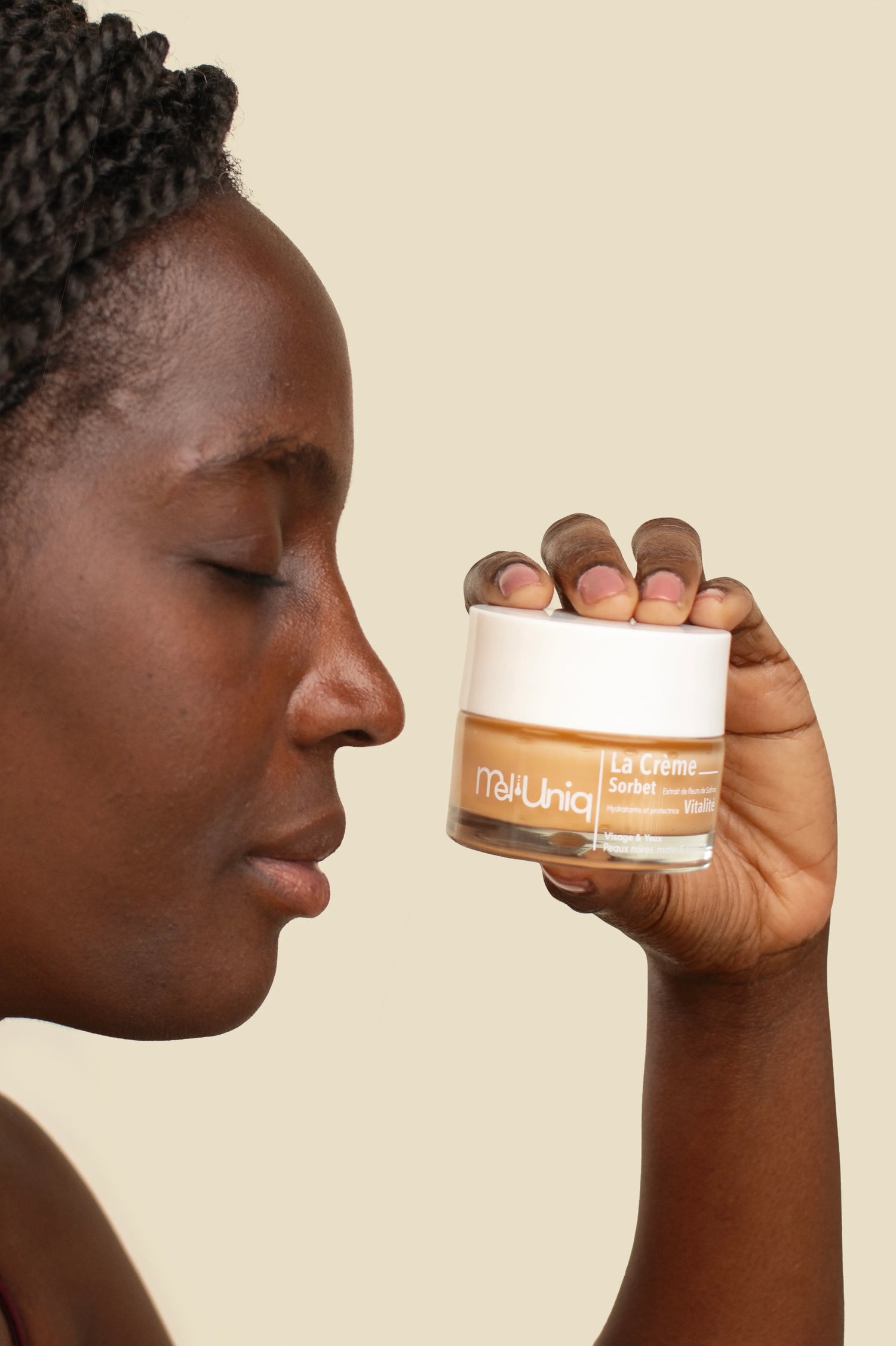 Femme à la peau noire tenant la crème hydratante Mel'Uniq Sorbet Vitalité près du visage