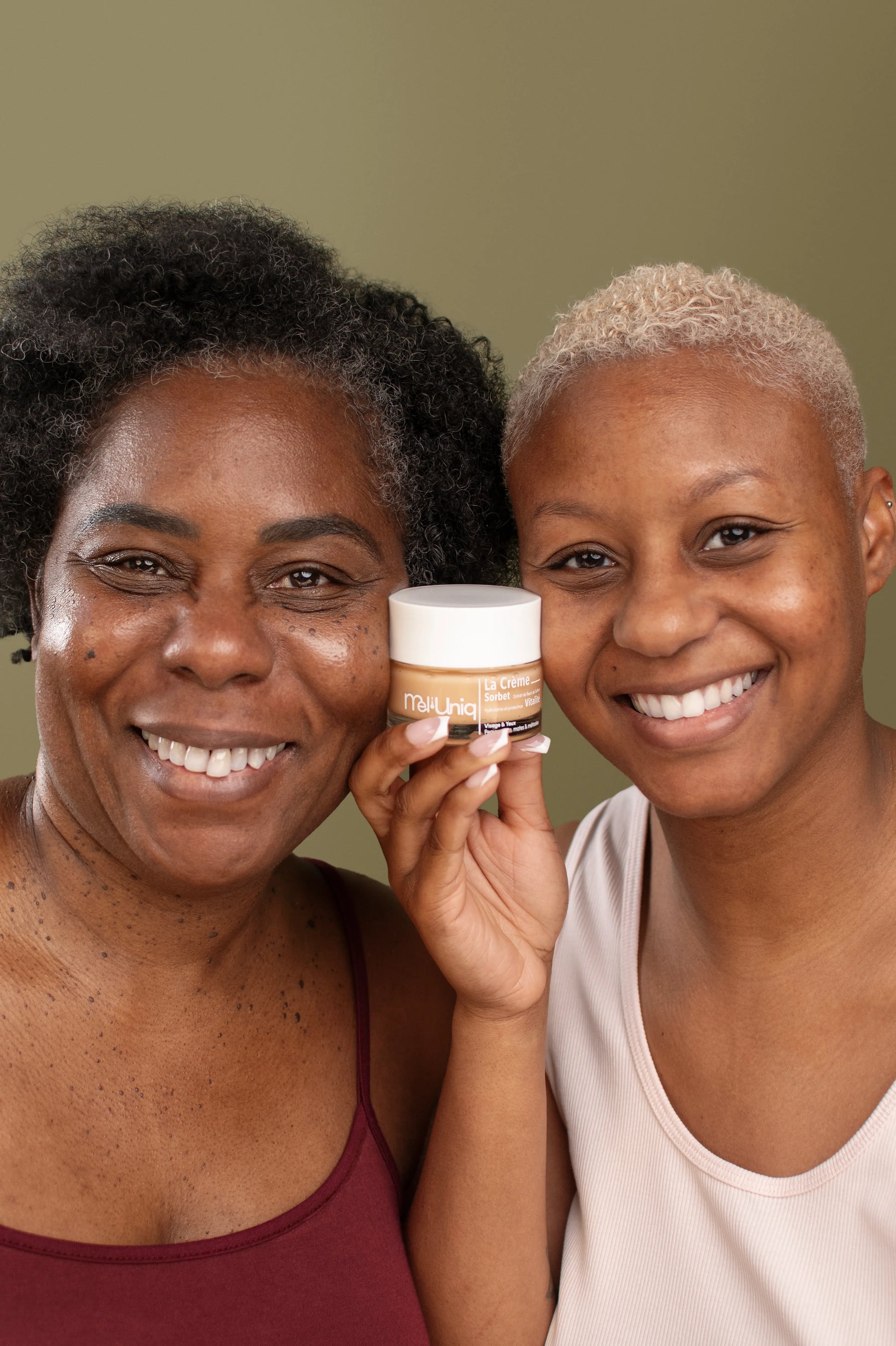 Deux femmes noires et métissées souriantes présentant la crème hydratante Mel'Uniq Sorbet Vitalité