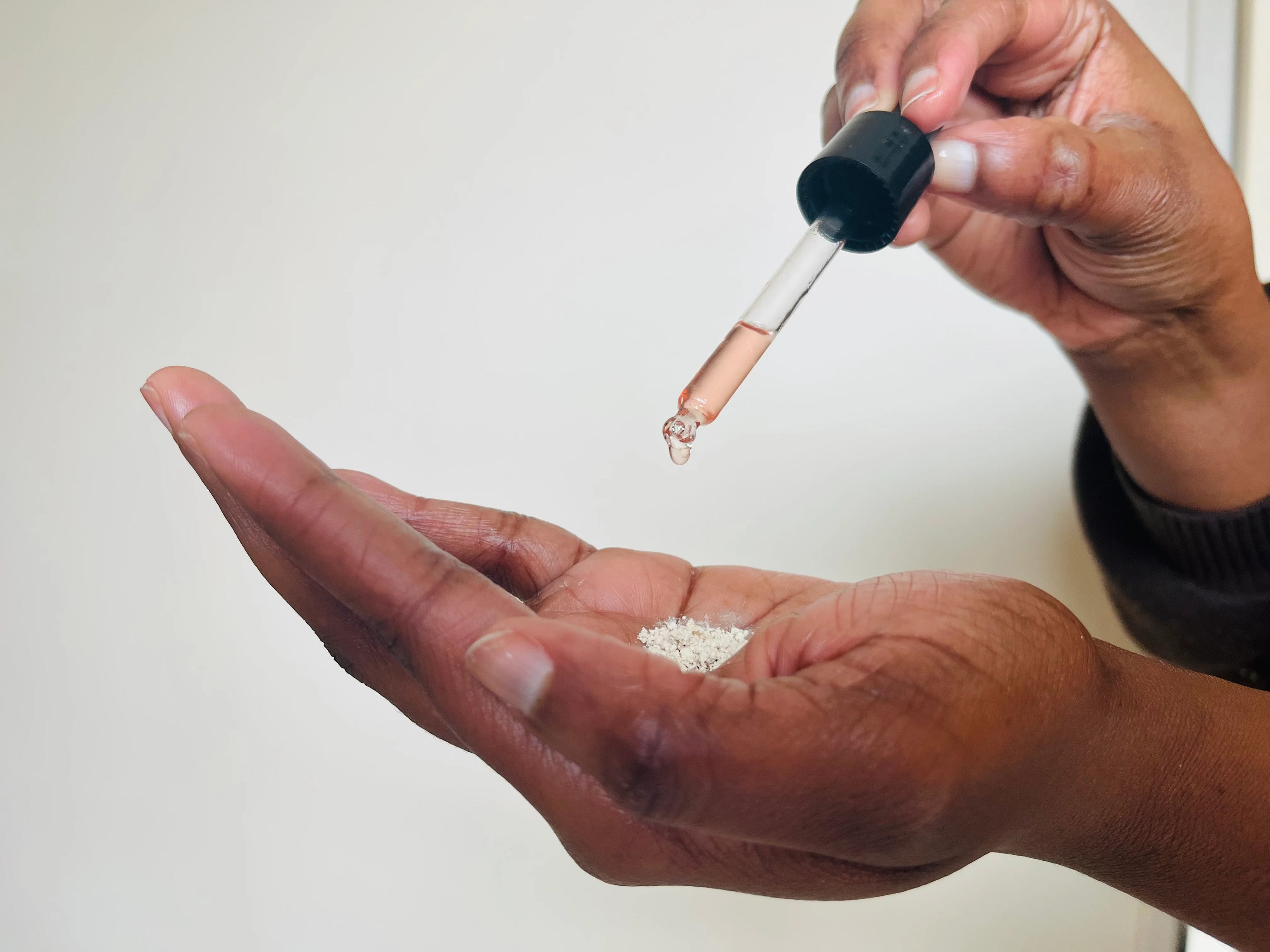 Main préparant la poudre correctrice avec quelques gouttes de sérum dans la routine anti-taches Mel’Uniq